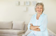 Senior woman with hands folded relaxing on sofa at home