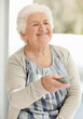 Mature woman holding remote control while watching television