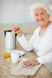 Happy elderly woman having her breakfast at home