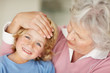Grandmother feeling the forehead of a happy boy