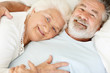 Loving mature female relaxing in bed with a happy senior man