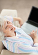 Happy mature woman working on laptop while looking at you