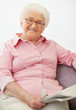 Relaxed mature female sitting on sofa as he holds a newspaper