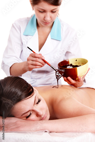 Photo: Girl having chocolate mask apply by beautician. Girl having chocolate mask apply by beautician.
