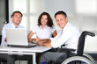 Foto: Businessman in wheelchair working in the office with colleagues Businessman in wheelchair working in the office with colleagues