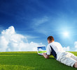 Young man use a notebook on green field