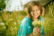 beautiful girl sitting in a field with a bouquet of flowers