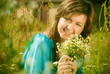 beautiful girl sitting in a field with a bouquet of flowers