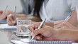 Close-up of hands jotting down notes at a conference