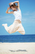 Teenage girl dancing hip-hop and jumping on beach, summer series