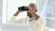 african businessman looking through binoculars in his office