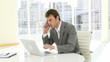 handsome businessman working with laptop and phone in his office