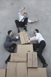 Photo: three business people balancing on cardboard boxes, smiling, portrait, elevated view three business people balancing on cardboard boxes, smiling, portrait, elevated view