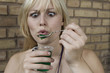 germany, berlin, young woman holding plastic cup with green jelly, porrait, close-up