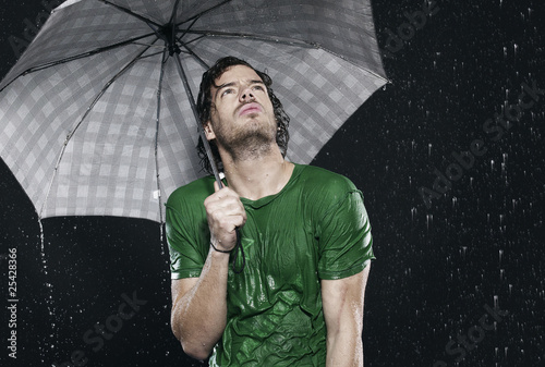 Photo: man standing in rain, holding umbrella. man standing in rain, holding umbrella.