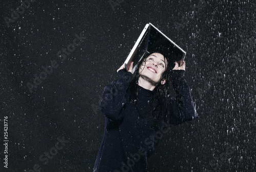 Photo: woman sheltering from rain under laptop. woman sheltering from rain under laptop.