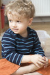 Photo: germany, berlin, boy (3-4) sitting on wooden floor, looking away, portrait, close-up germany, berlin, boy (3-4) sitting on wooden floor, looking away, portrait, close-up