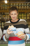 Photo: germany, bavaria, munich, man in front of market stall holding bread rolls, portrait germany, bavaria, munich, man in front of market stall holding bread rolls, portrait