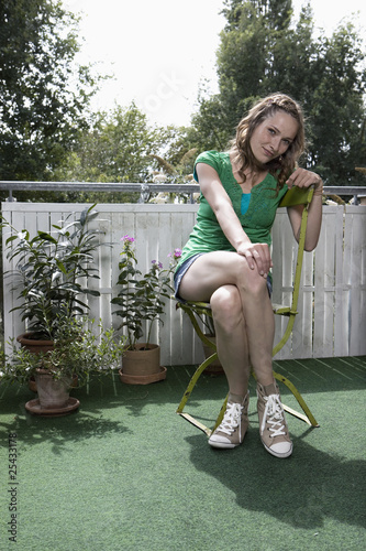 Photo: germany, berlin, young woman sitting on chair in balcony, portrait germany, berlin, young woman sitting on chair in balcony, portrait