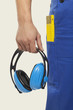 man in overall holding ear muff, mid section, close-up