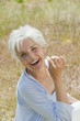 Foto: spain, mallorca, senior woman sitting in meadow, holding blade of grass, laughing, elevated view spain, mallorca, senior woman sitting in meadow, holding blade of grass, laughing, elevated view