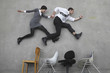 Foto: businessman and businesswoman hand in hands, jumping over chairs, side view, elevated view businessman and businesswoman hand in hands, jumping over chairs, side view, elevated view