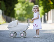 germany, bavaria, girl (2-3) playing with toy baby carriage