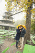 Foto: germany, bavaria, munich, english garden, couple in rainy garden holding umbrella with chinese tower in background germany, bavaria, munich, english garden, couple in rainy garden holding umbrella with chinese tower in background