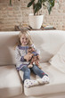 germany, cologne, girl (4-5) with a stuffed toy, sitting on sofa
