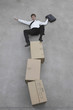 Photo: businessman balancing on stack of cardboard boxes, portrait, elevated view businessman balancing on stack of cardboard boxes, portrait, elevated view