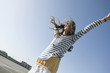 germany, berlin, young woman on parking level, raising arms, smiling, portrait