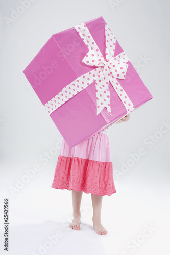 Photo: girl (4-5) holding gift in front of her face girl (4-5) holding gift in front of her face