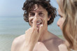 spain, mallorca, woman applying suncream on man's nose