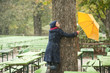 Foto: germany, bavaria, munich, english garden, woman in beer garden embracing tree, holding umbrella, laughing germany, bavaria, munich, english garden, woman in beer garden embracing tree, holding umbrella, laughing