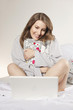 woman sitting on bed holding pillow and with laptop