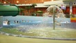 People bathe in pool with a fountain in indoor water park People bathe in pool with a fountain in indoor water park