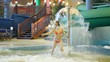 Charming woman runs under fountain in pool in indoor water park Charming woman runs under fountain in pool in indoor water park