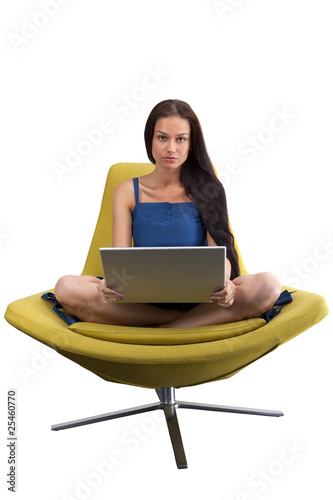 Photo: Young female sitting in the fashionable chair with laptop Young female sitting in the fashionable chair with laptop