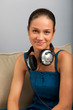 Young female sitting on the sofa with headphones on her neck