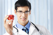 Happy smiling doctor with apple, at office