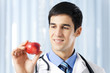 Happy smiling doctor with apple, at office