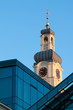 Old clock tower behind modern glass buinding