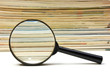 magnifying glass and stack of magazines