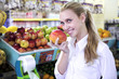 Woman smelling a mango in the supermarket