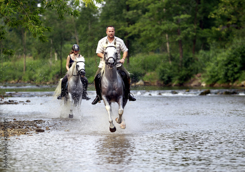 Foto: Ein Mann und eine Frau reiten durch eine Fluss Ein Mann und eine Frau reiten durch eine Fluss