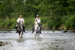 Ein Mann und eine Frau reiten durch eine Fluss