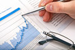 Businessman's hand showing diagram on financial report with pen.