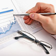 Businessman's hand showing diagram on financial report with pen.