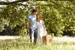 A young couple carrying a picnic basket