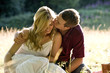A young couple sitting on the grass, kissing